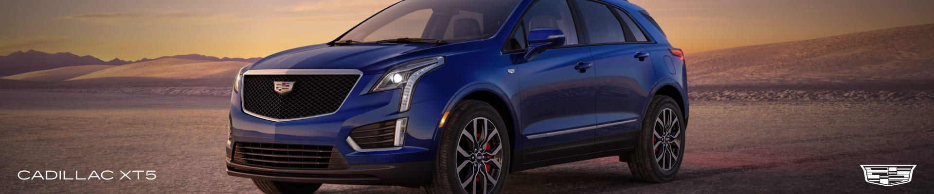 Blue Cadillac XT5 shown against a desert landscape at sunset.