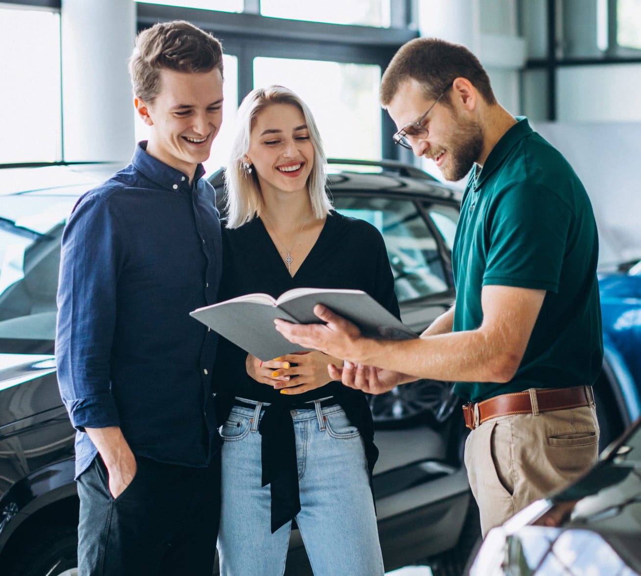 A dealership representative reviewing a document with a smiling couple inside a bright showroom.