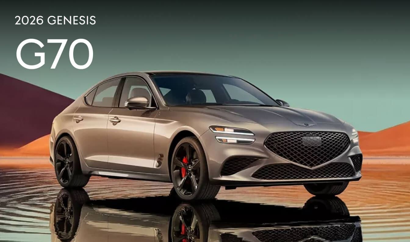 A beige 2026 Genesis G70 parked in a desert oasis with a bright blue sky background.