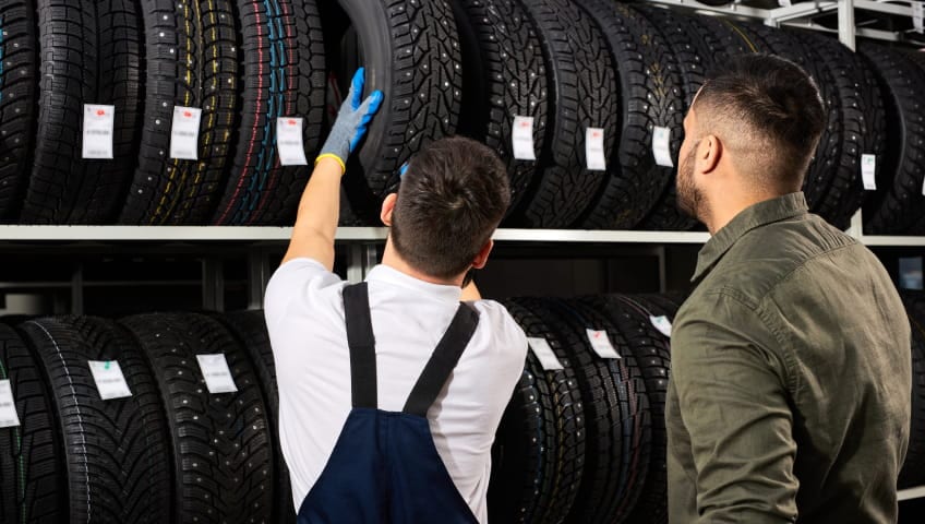 Technician helping a customer select tires from a display rack.