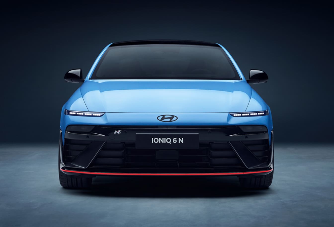 A front exterior view of a blue IONIQ 6 parked with a plain dark concrete background.