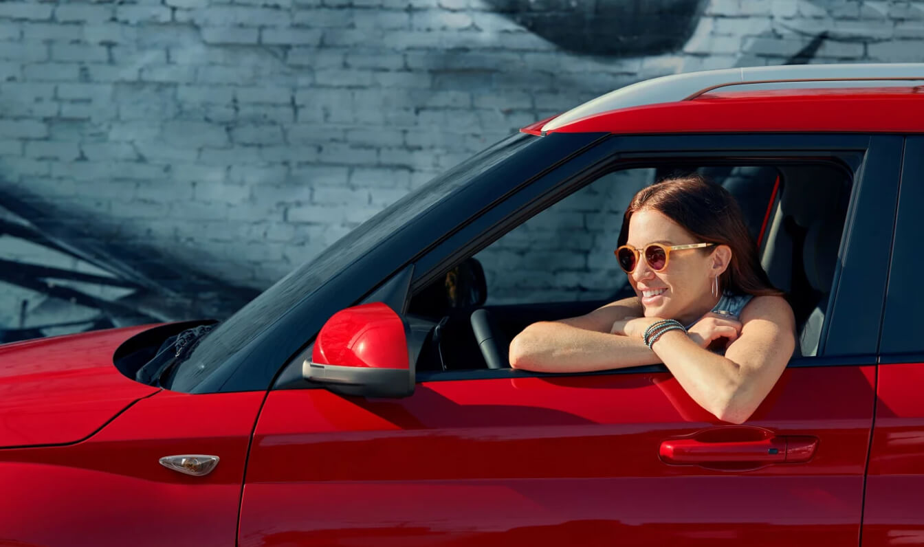A woman smiles behind the wheel of a red Hyundai Venue