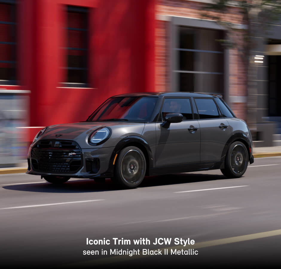 2026 MINI Cooper S Iconic Trim with JCW Style in Midnight Black II Metallic, driving through a city street.