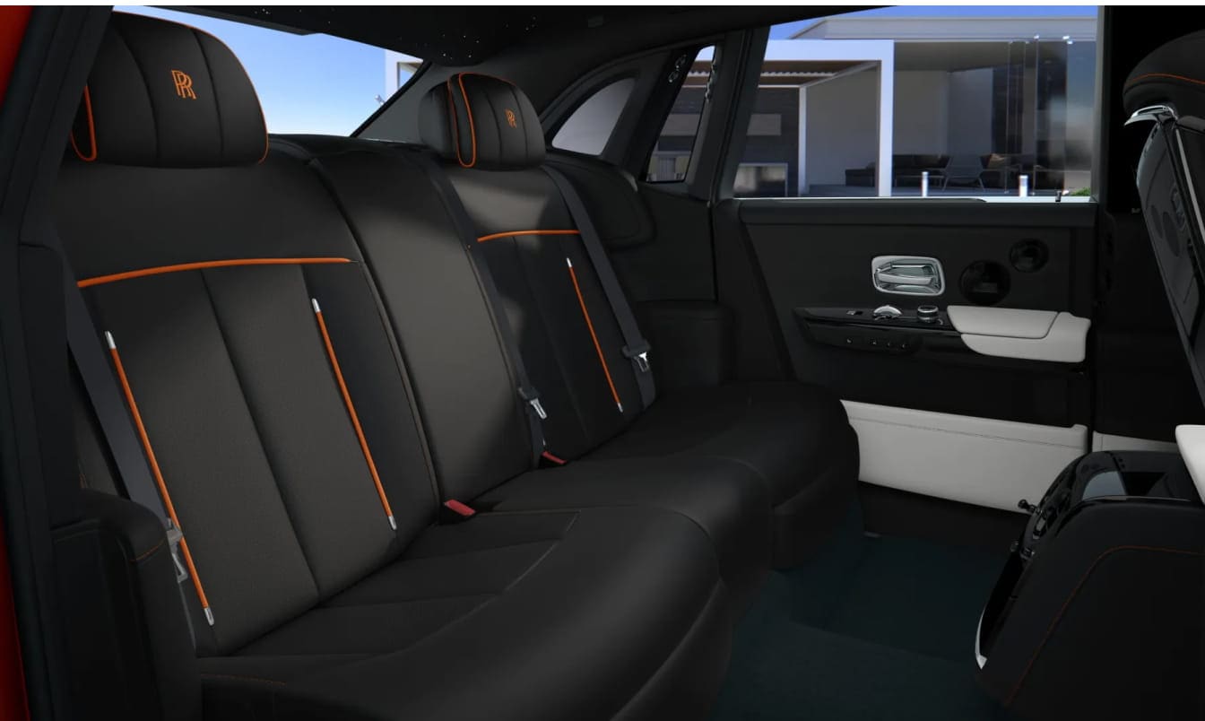2026 Rolls-Royce Phantom car interior with black leather seats accented by orange piping and embroidered headrests. Sleek design, exudes elegance and comfort.