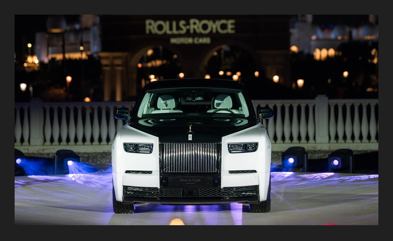 Direct front view of a 2027 Rolls-Royce Phantom Series II featuring a two-tone Arctic White and Diamond Black finish with illuminated Pantheon grille.