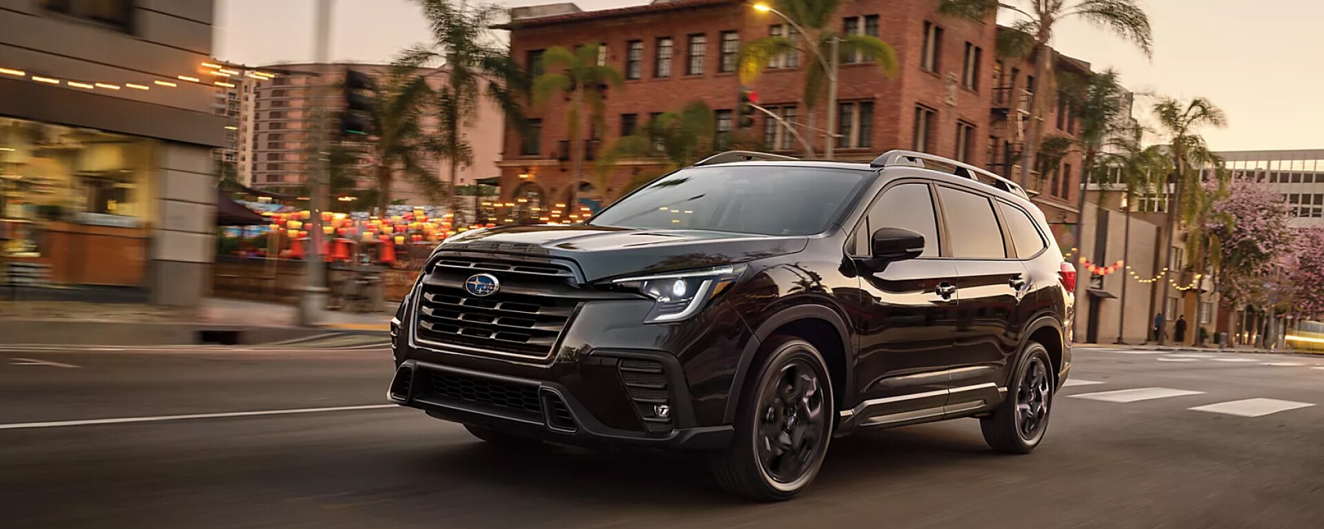 2025 Subaru Ascent in black driving through town streets at dusk near Danbury, CT
