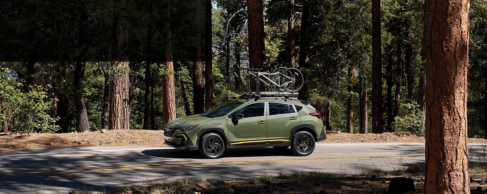 Green 2025 Subaru Crosstrek carrying bikes through woods near Danbury, CT