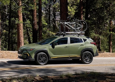 Green 2025 Subaru Crosstrek carrying bikes through woods near Danbury, CT