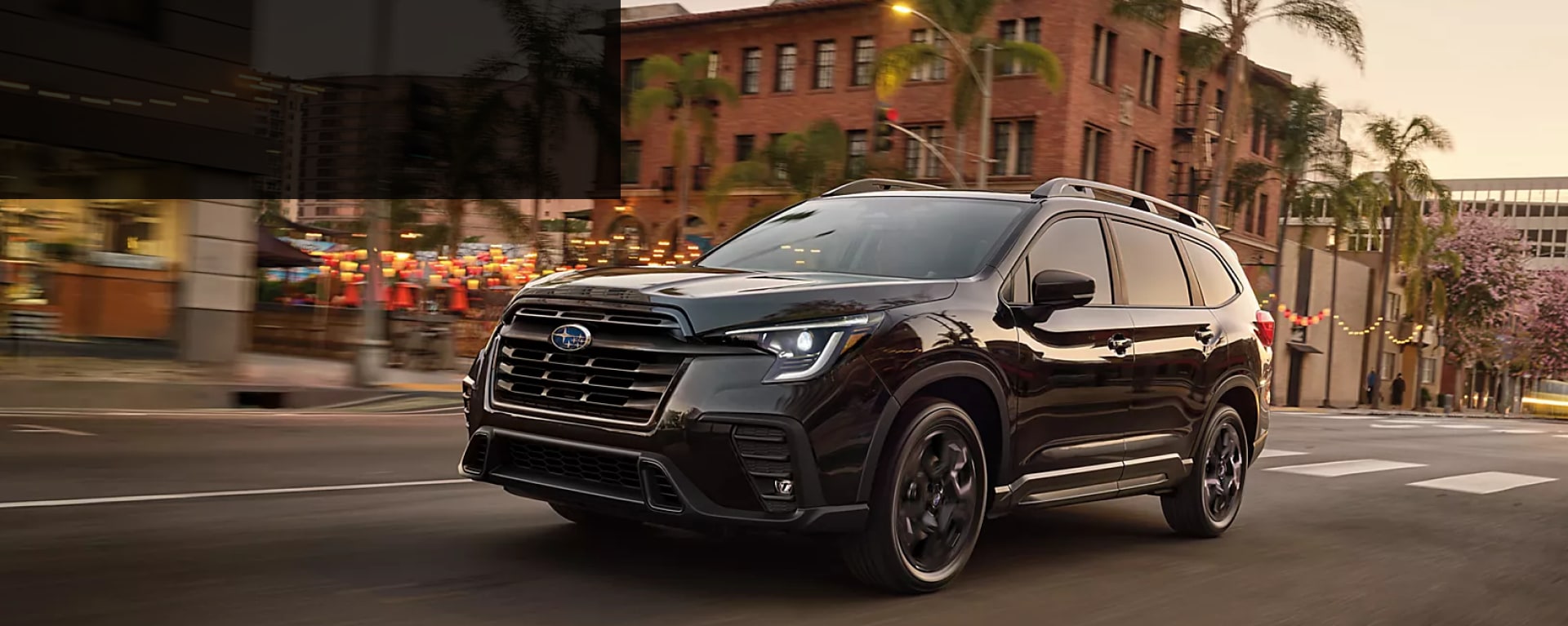 2025 Subaru Ascent in black driving through town streets at dusk near Danbury, CT