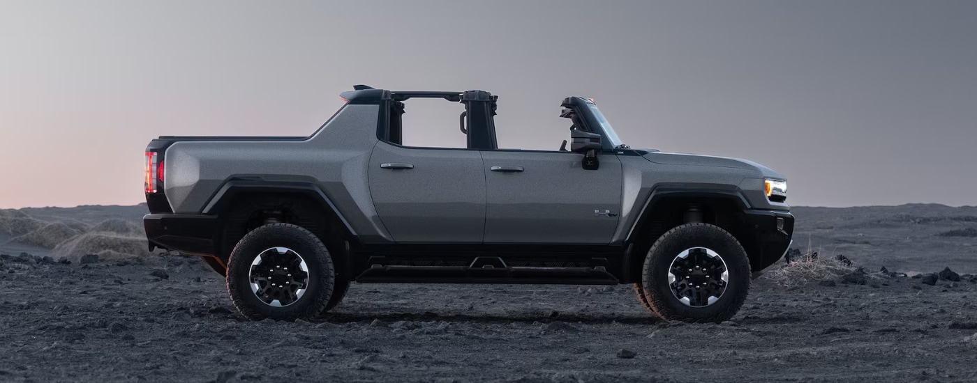 Side profile of a silver 2026 GMC Hummer EV Truck parked off-road