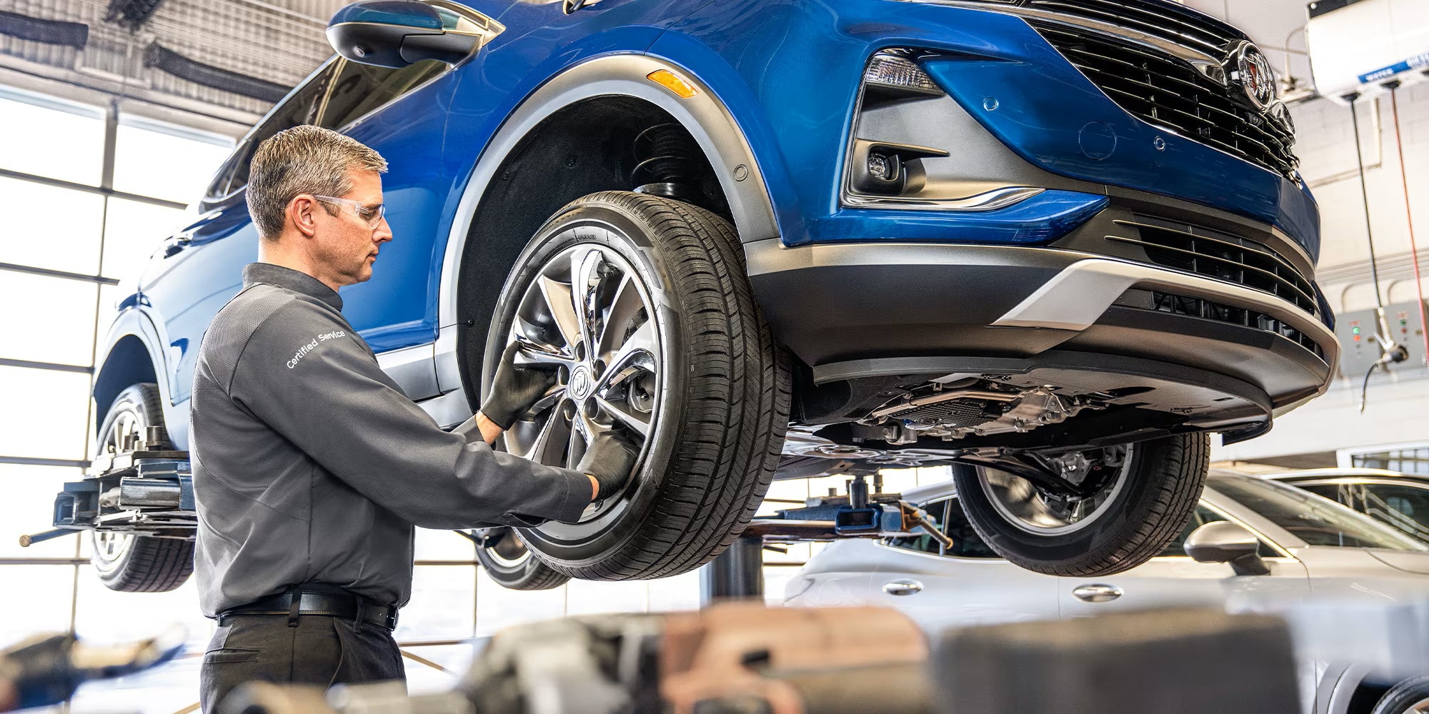 Certified Service technician rotating a tire on a Buick SUV at Brickell Buick GMC in Miami