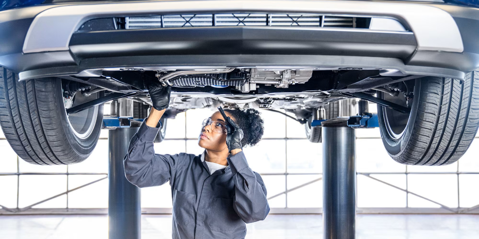 Certified Service technician inspecting a lifted Buick during a Spend and Save service visit at Brickell Buick GMC in Miami