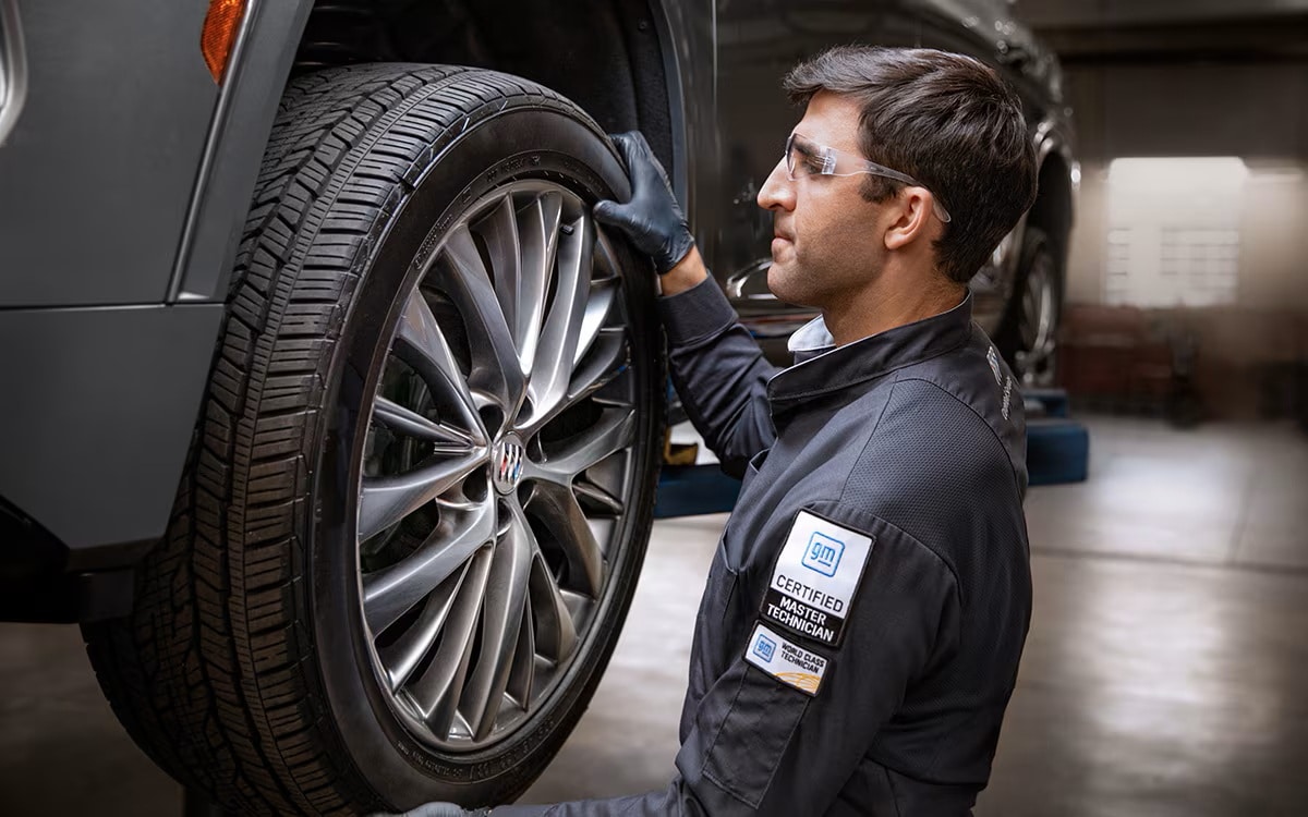 Certified Service technician working on a Buick alloy wheel during a front-end alignment at Brickell Buick GMC