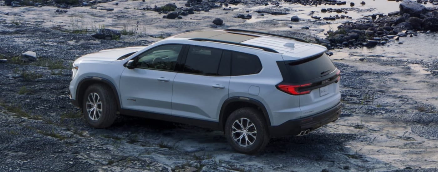A white 2025 GMC Acadia AT4 parked on a shore.