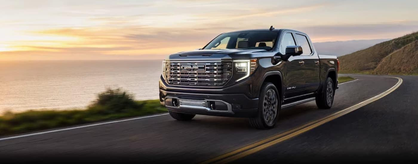 A black 2024 GMC Sierra 1500 driving near an ocean.