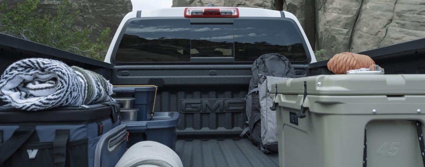 Gear loaded into the bed of a white 2023 GMC Canyon AT4.