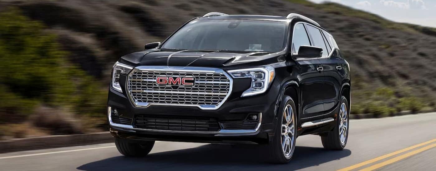 A black 2024 GMC Terrain driving to view a GMC for sale.