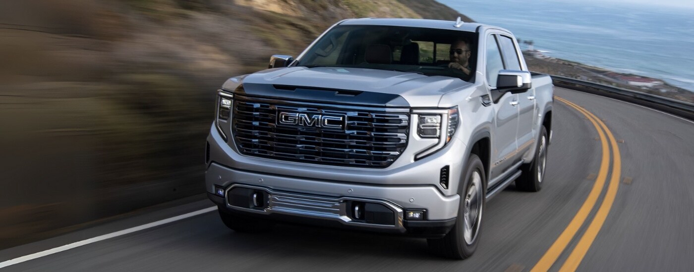A silver 2024 GMC Sierra 1500 for sale rounding a corner.