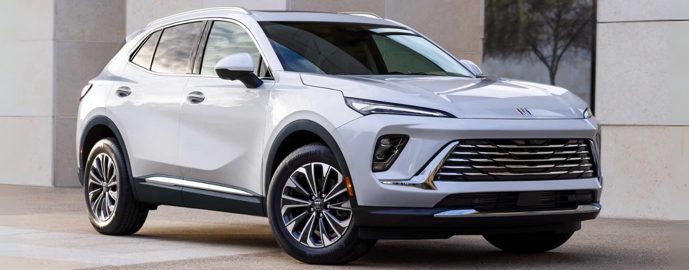 A white 2024 Buick Envision for sale parked in front of a building.