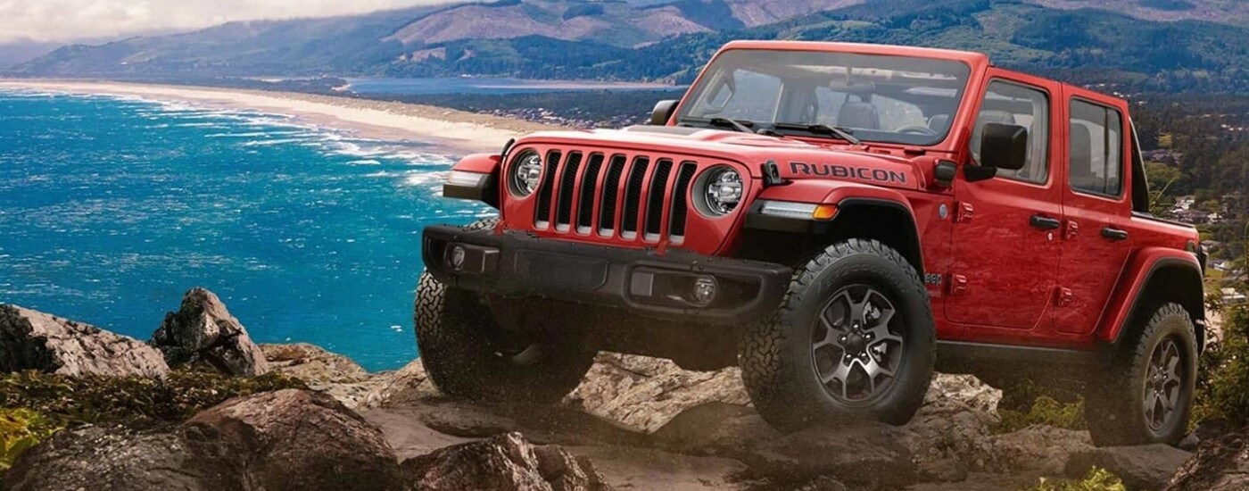 A red 2023 Jeep Wrangler for sale is shown off-road.