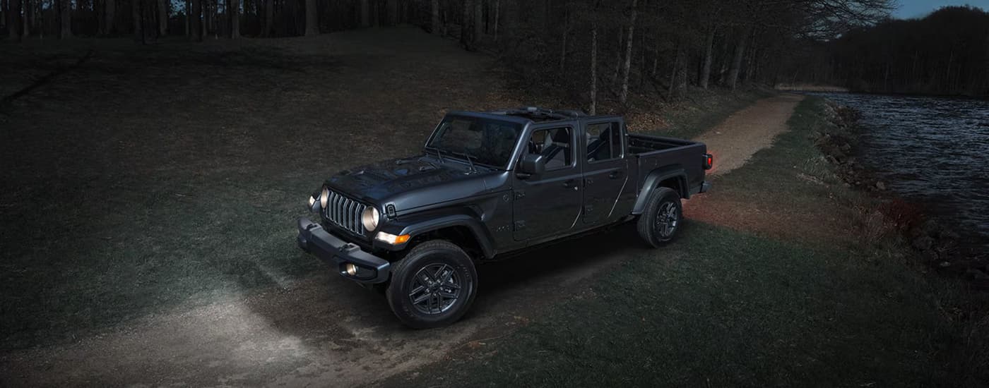 Black 2026 Jeep Gladiator driving on a dirt road at night