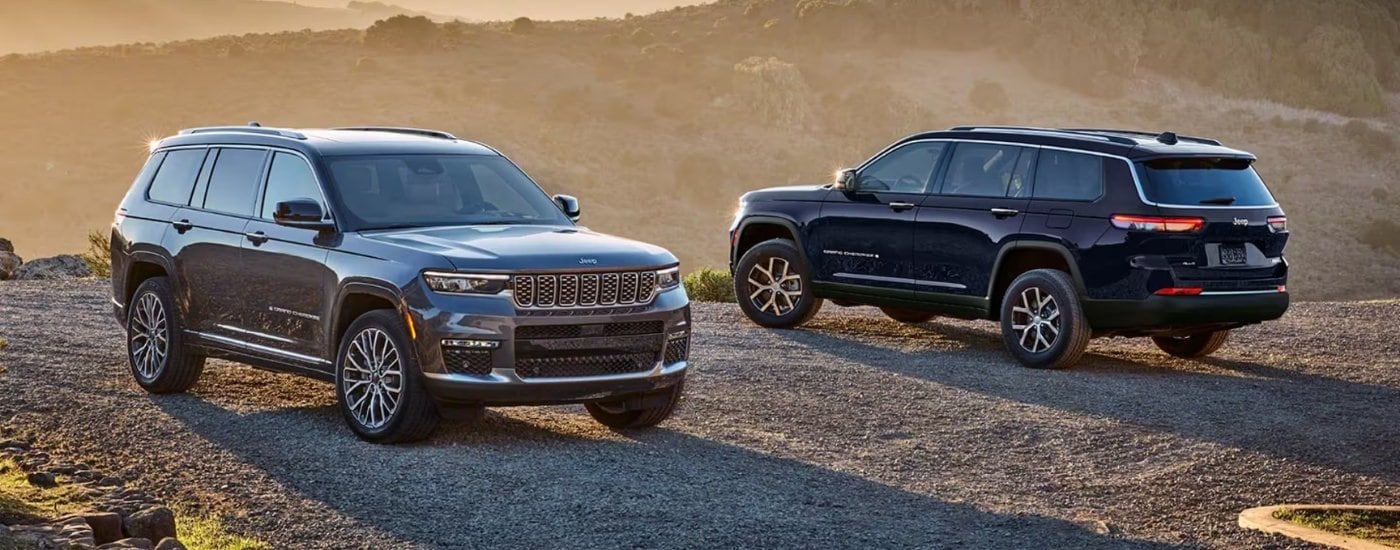 A grey and a blue 2025 Jeep Grand Cherokee parked off-road.