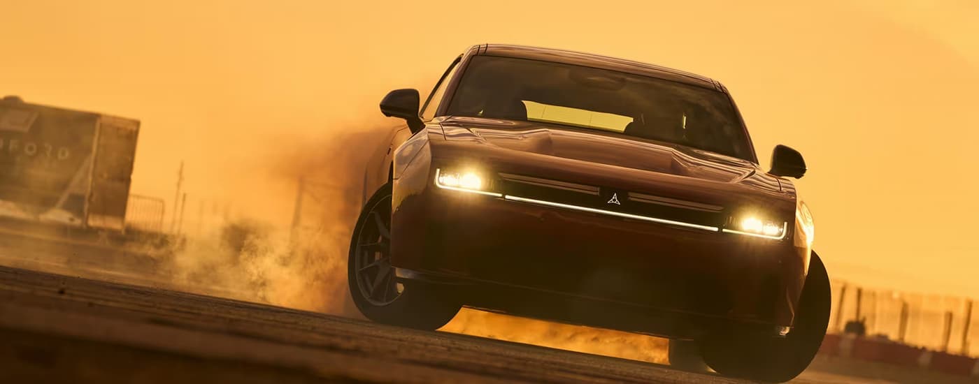 Red 2025 Dodge Charger Daytona driving on a track during a sunset