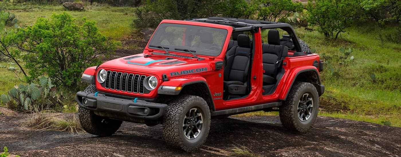 Red 2025 Jeep Wrangler Rubicon parked near grass.