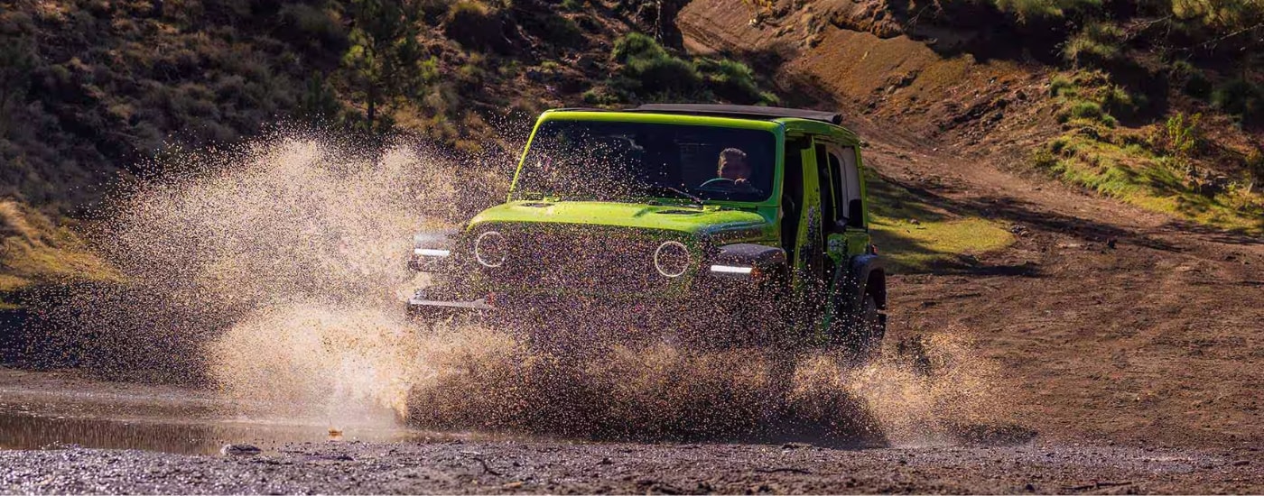 Green 2026 Jeep Wrangler driving through water