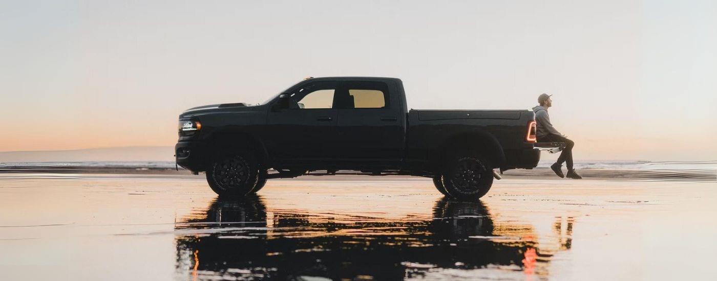 Black 2023 Ram 2500 parked on a beach at dusk