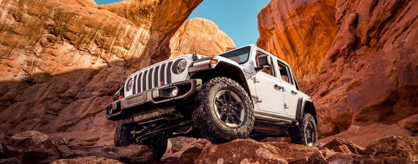 A white 2025 Jeep Wrangler driving on rocks.