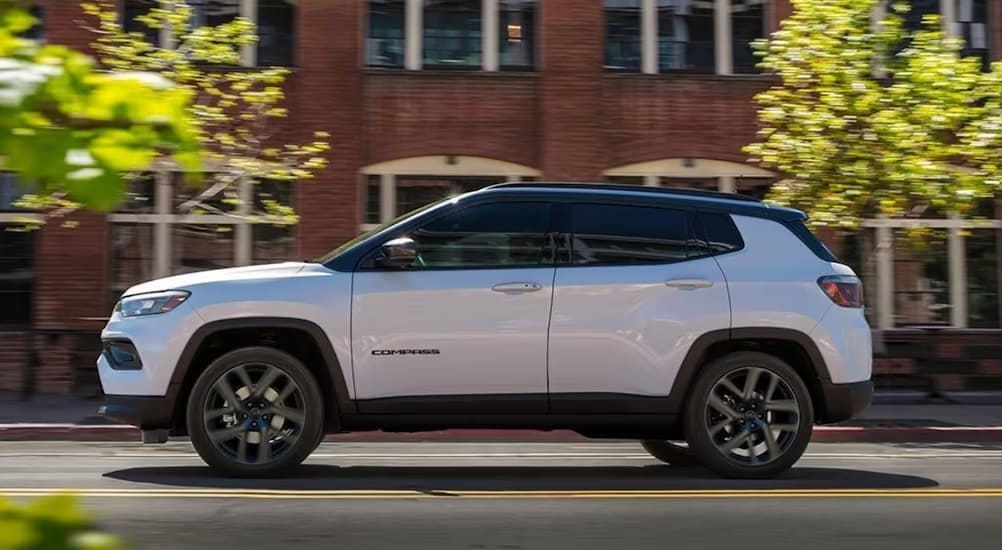A white 2026 Jeep Compass driving in a city.
