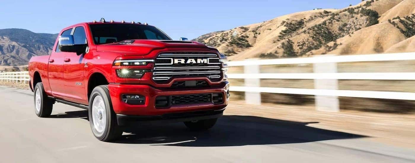 Red 2026 Ram 2500 LARAMIE driving along a fence