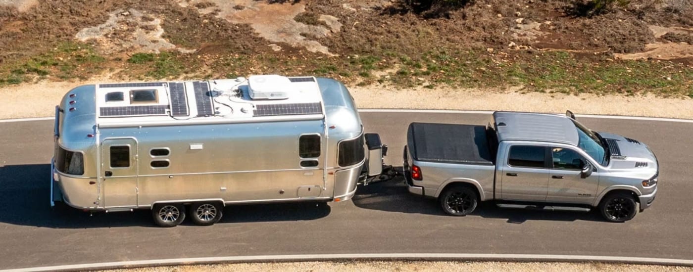 A silver 2025 Ram 1500 towing a trailer.