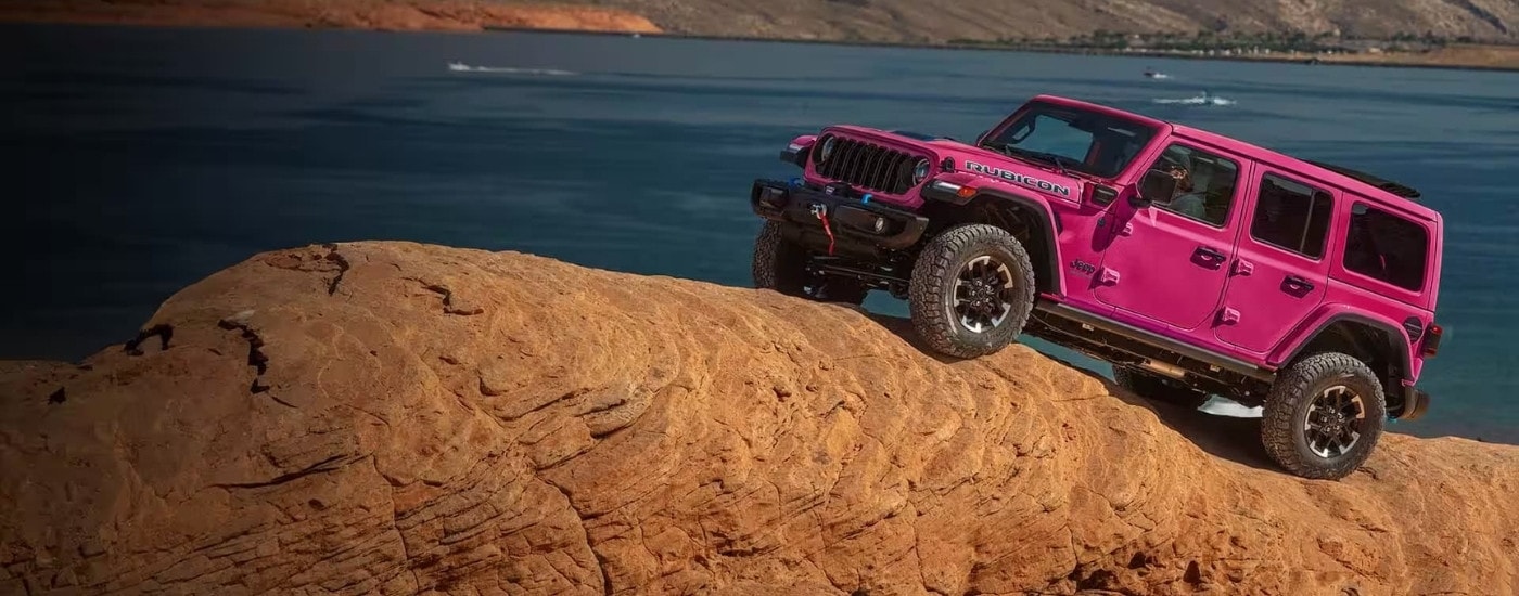 A pink 2024 Jeep Wrangler 4xe Rubicon is driving off-road.