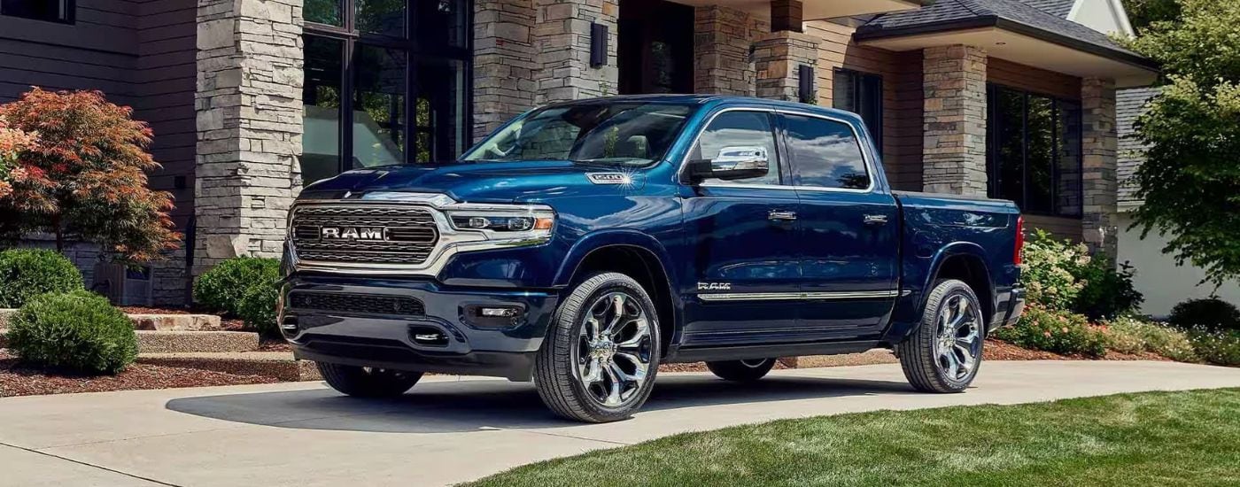 Blue 2023 Ram 1500 Limited Elite edition parked in front of a home