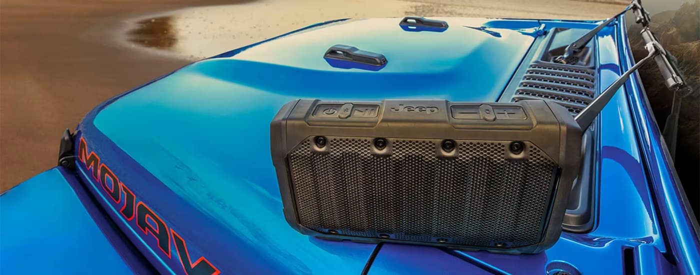 Green speaker box on the hood of a blue 2026 Jeep Gladiator