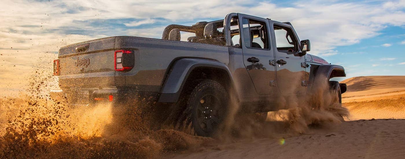Grey 2026 Jeep Gladiator kicking up sand on a beach