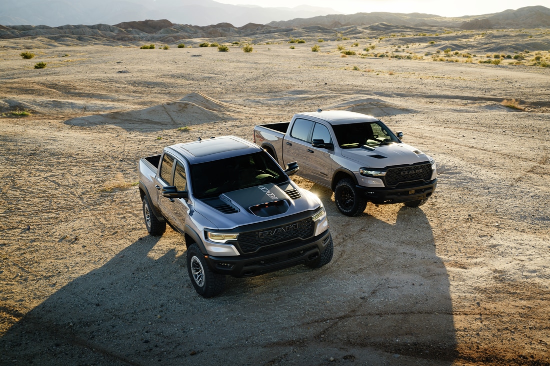 2025_1500_RHO_in_Billet_Silver_and_a_2025_1500_Rebel_X_in_Mojave_Sand_parked_off_road.png