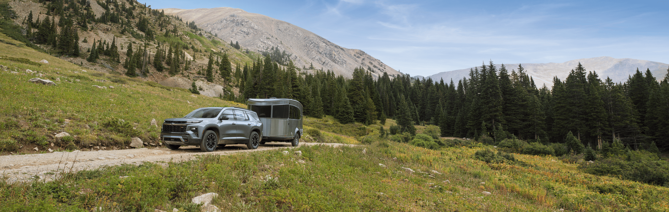 Chevrolet Traverse Chevrolet Traverse towing a camper trailer on a dirt road.