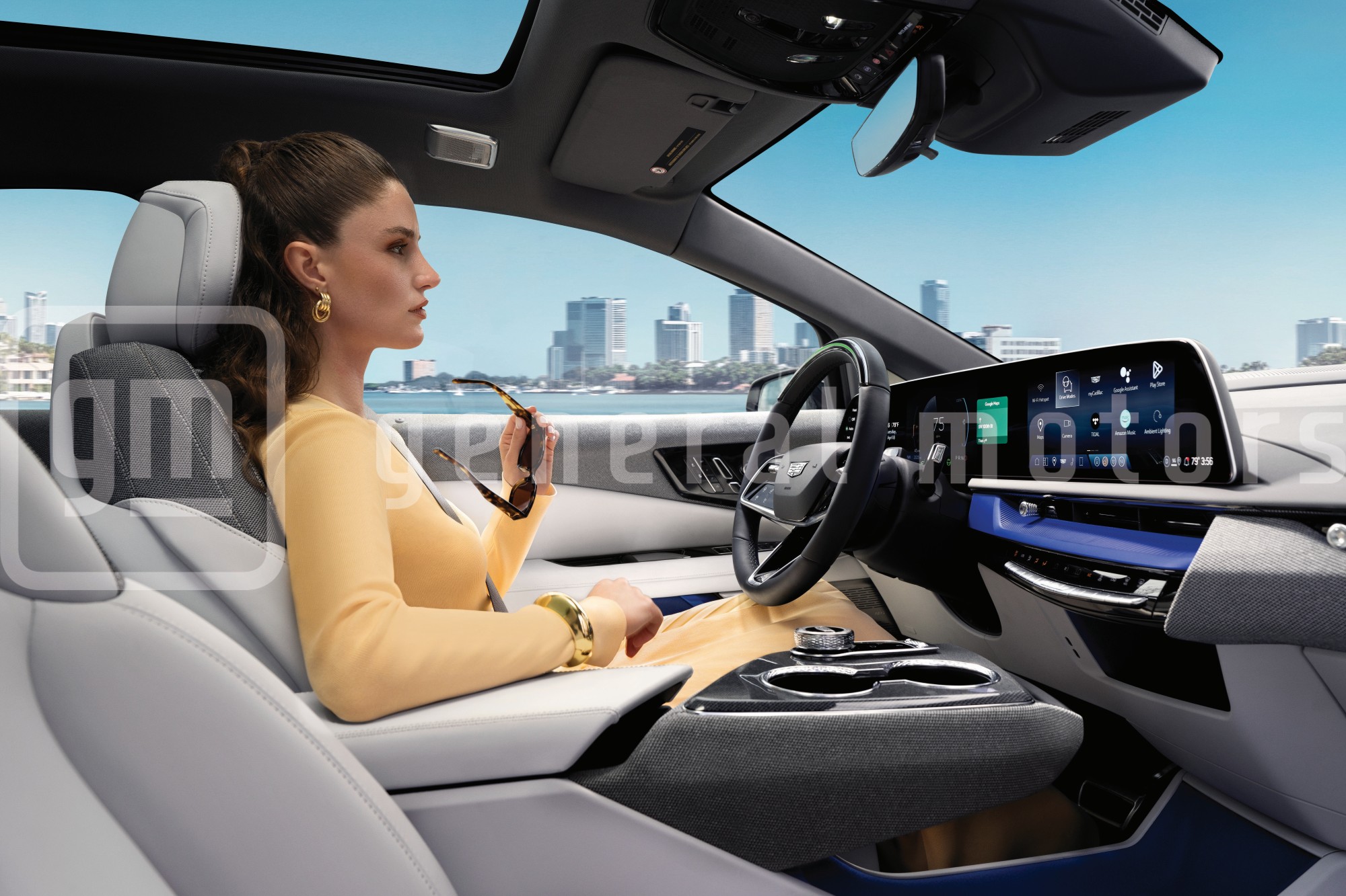 Passenger View of a Woman Driving a Cadillac OPTIQ Past the City While Utilizing Super Cruise Hands-free Technology