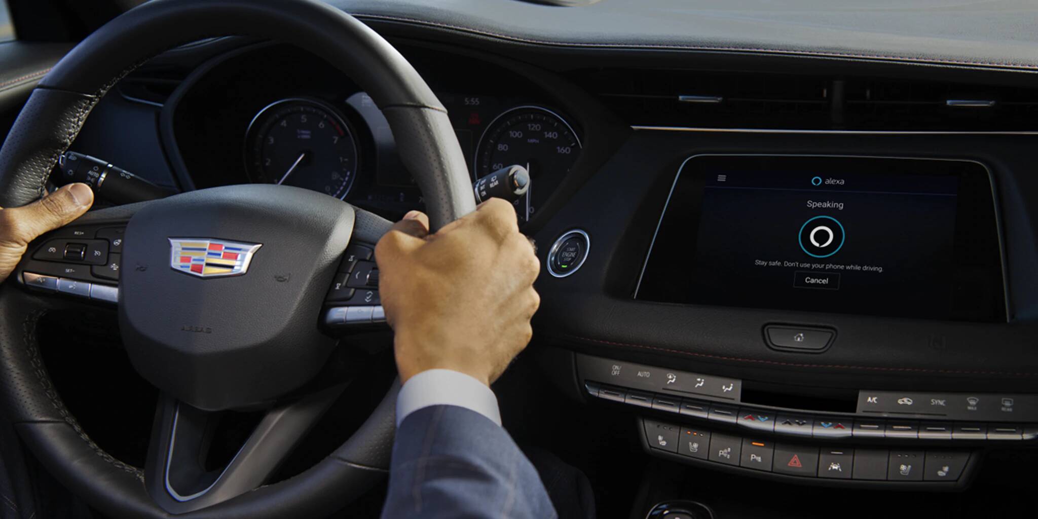 les mains d'un homme au volant du Cadillac XT4 incluant l'application Alexa sur l'écran central du tableau de bord