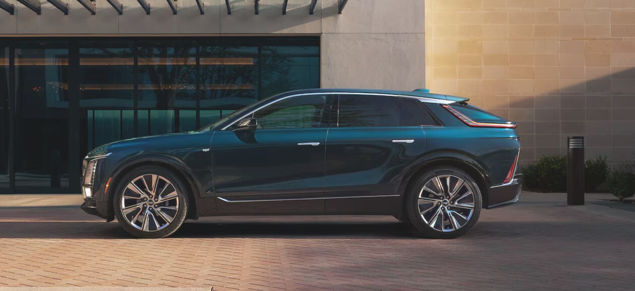 A dark blue 2025 Cadillac LYRIQ parked in front of a large building