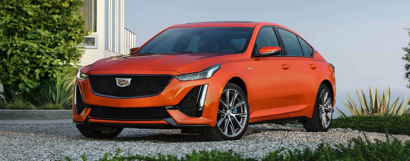 An orange 2022 Cadillac CT5-V Blackwing is shown parked on a gravel driveway.