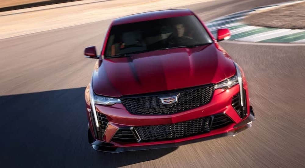 A red 2024 Cadillac CT4-V Blackwing is shown driving on a racetrack.