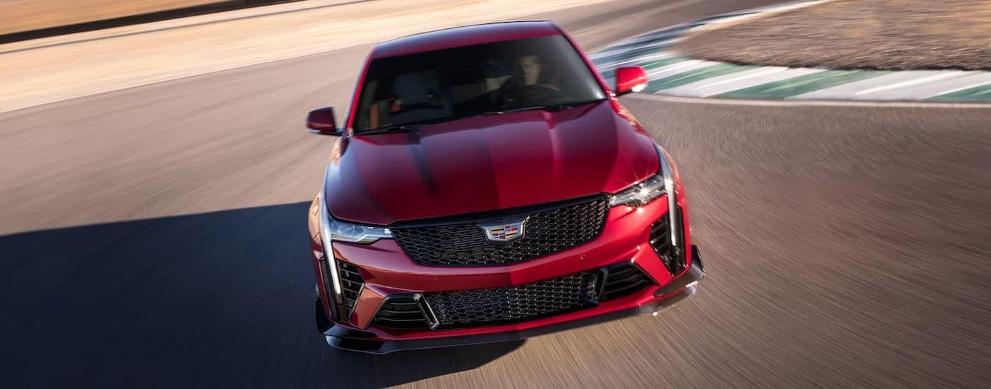 A red 2023 Cadillac CT4-V Blackwing is shown driving on a track after leaving a Cadillac dealer.