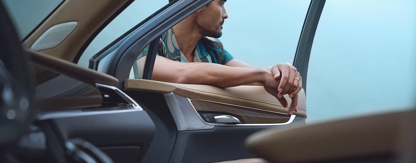 A man is shown leaning on the open door of a Cadillac XT6 for sale.