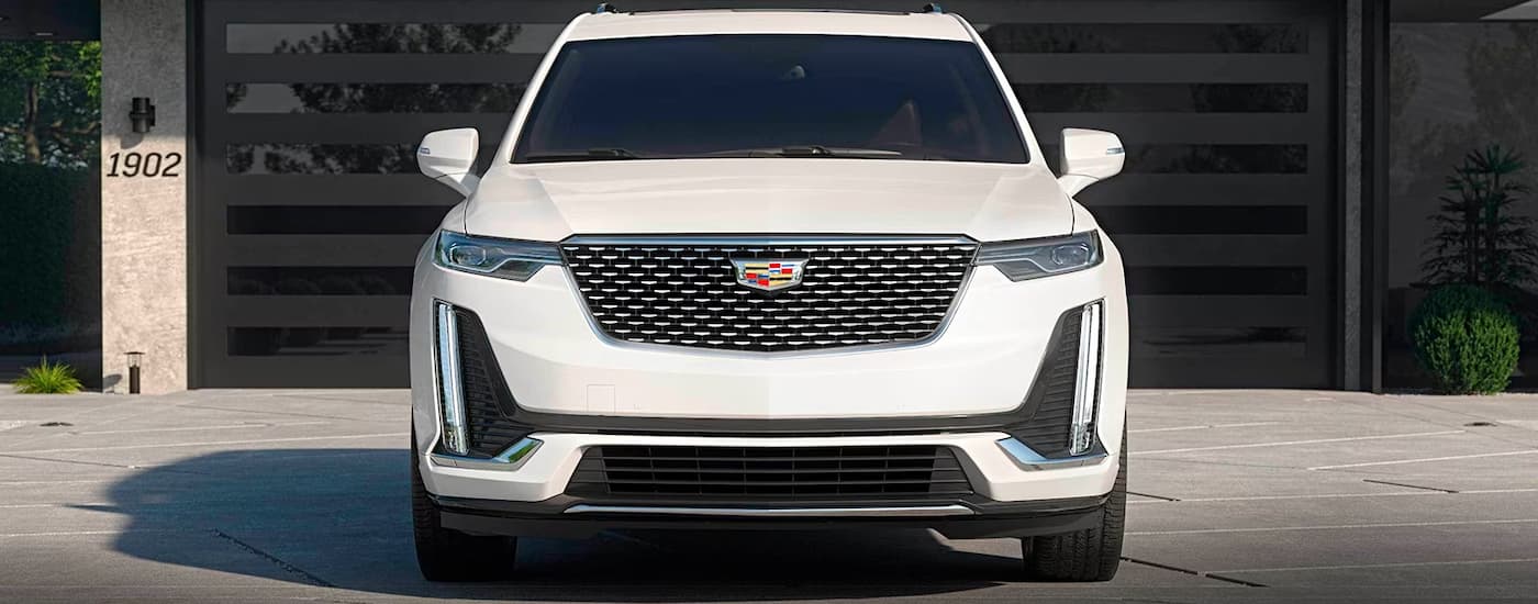 A white 2024 Cadillac XT6 is shown from the front parked on a driveway.