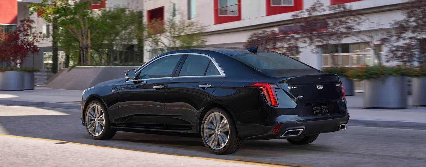 A black 2024 Cadillac CT4 is driving on a city street.