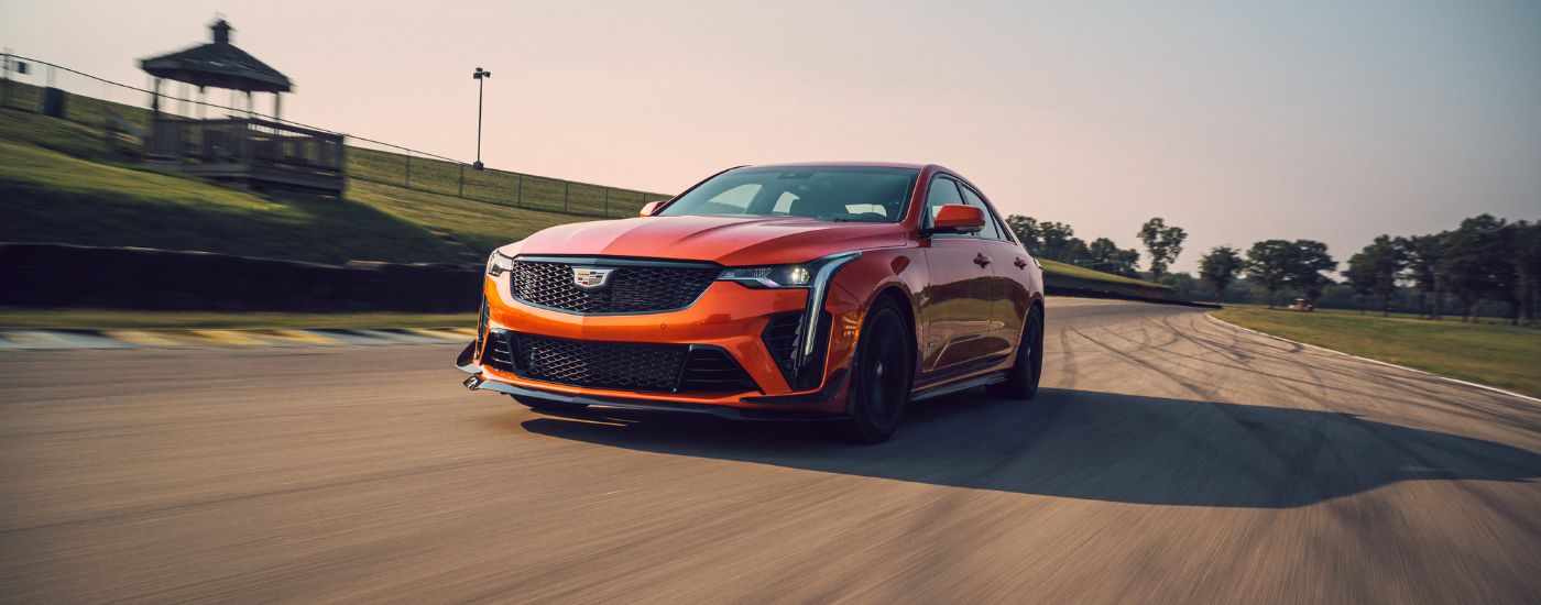 An orange 2023 Cadillac CT4-V Blackwing is shown on a racetrack after leaving a Cadillac dealer near Brooklyn Heights.